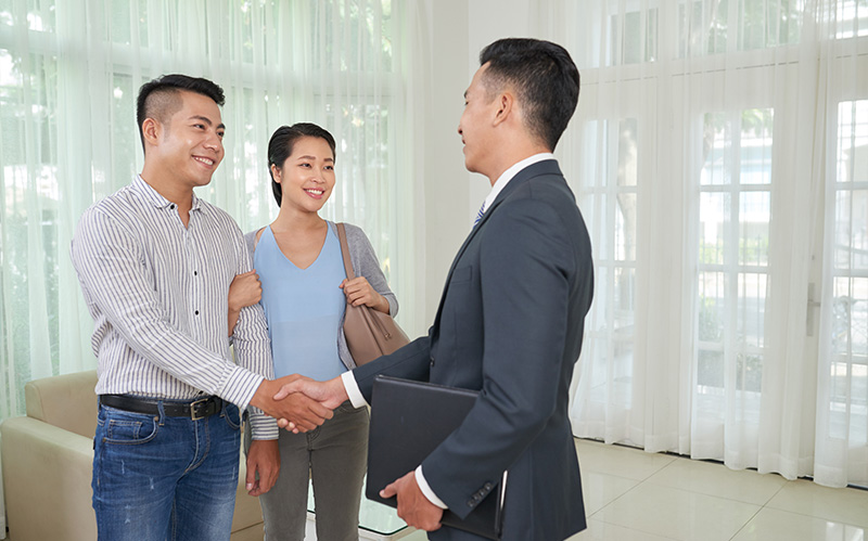 Real estate agent shaking hands with a happy young couple
