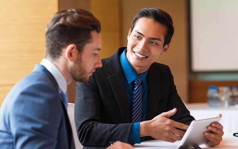 Professional presenting tablet data to colleague during meeting