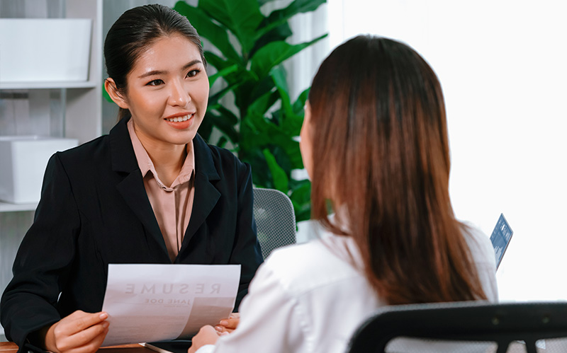 HR manager interviewing a female job candidate holding resume