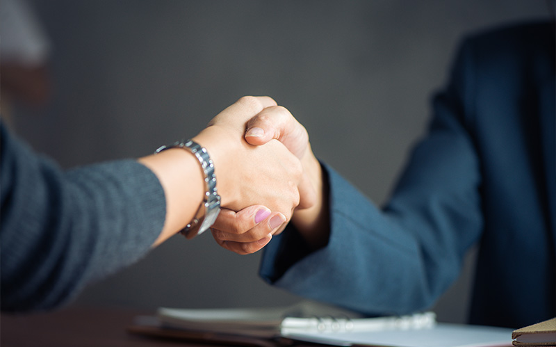 Close up of two business professionals shaking hands after completing a deal