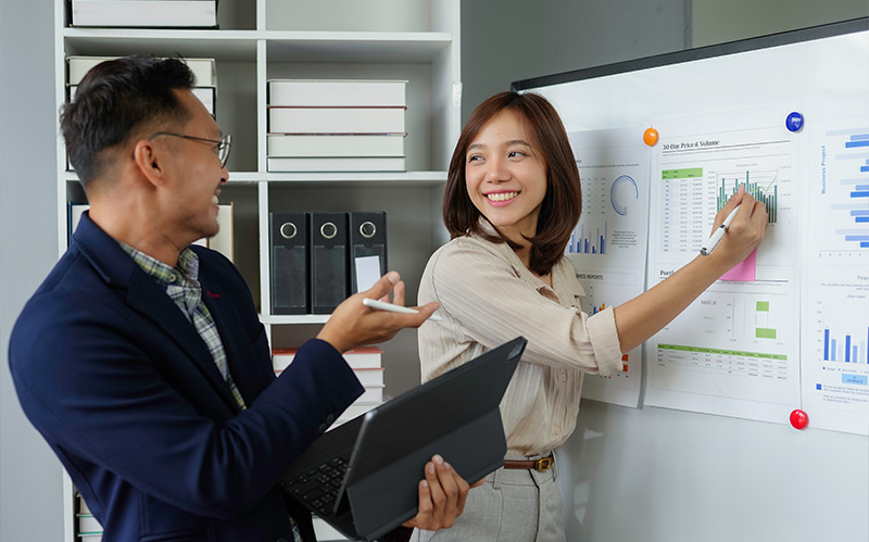 Business colleagues reviewing sales charts and behavioral data on whiteboard