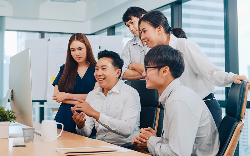 Team collaborating around computer in modern office.