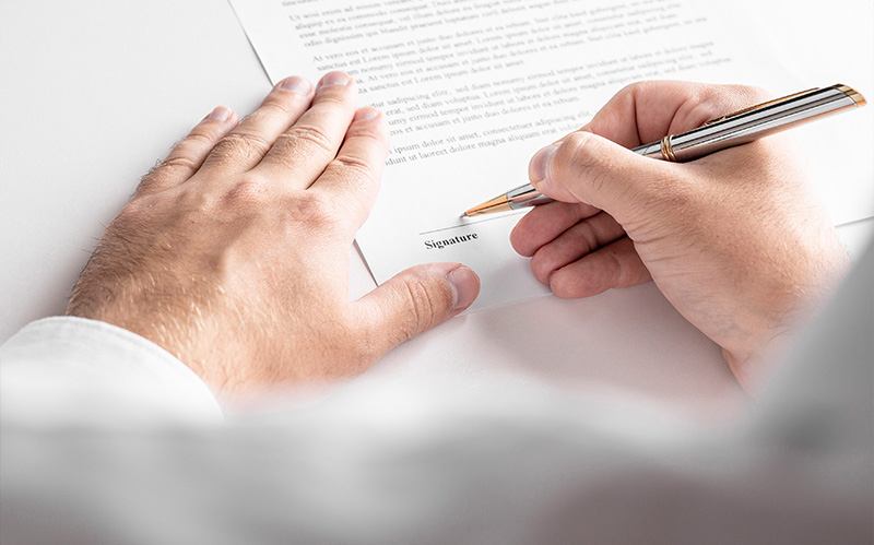 Close up of hands holding pen signing formal business document