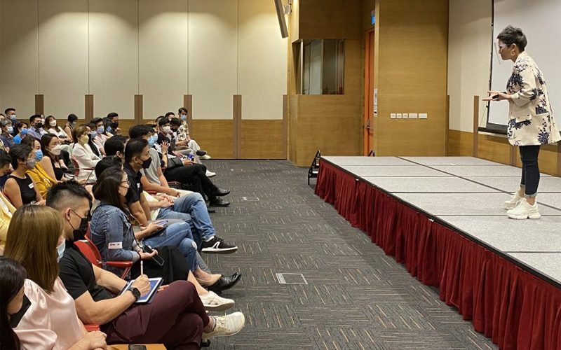Speaker presenting to an audience at an indoor event.