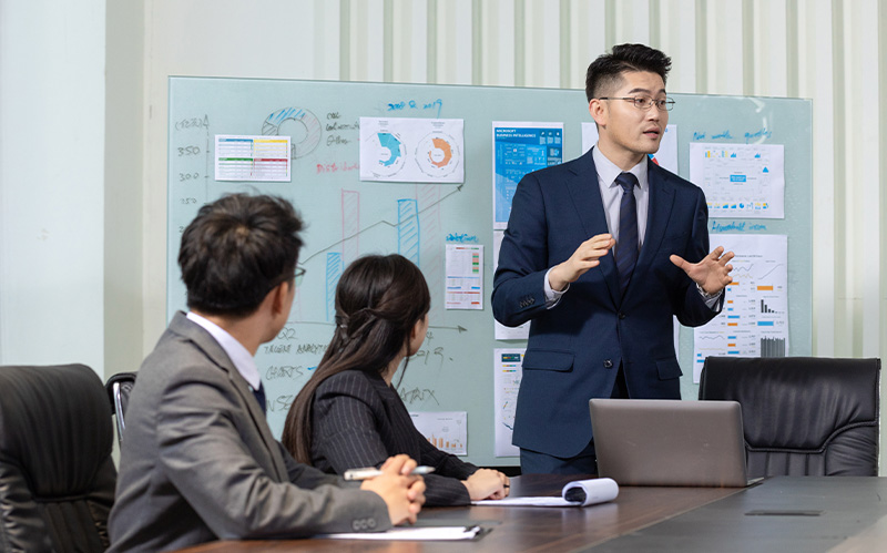 Business executive presenting data on whiteboard to team